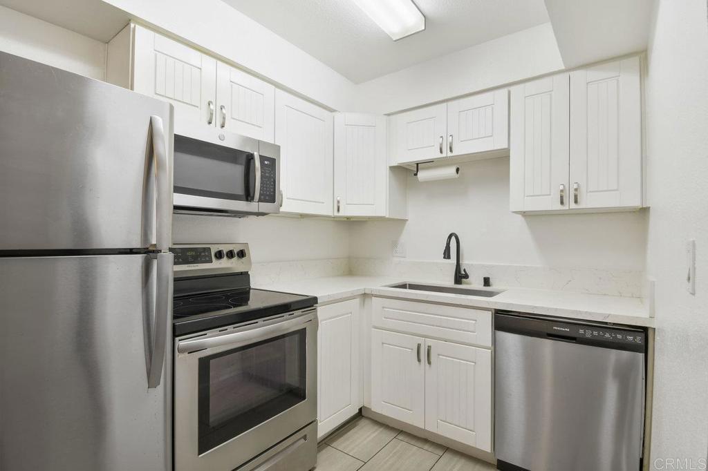 a kitchen with white cabinets stainless steel appliances and sink