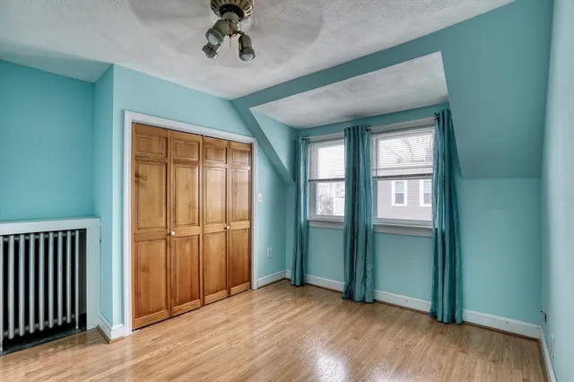 an empty room with wooden floor closet and windows