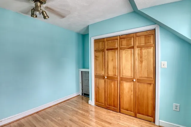 an empty room with wooden floor closet and windows