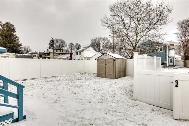 a view of a dry yard covered with snow in front of house