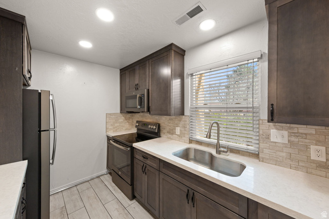 301 South 1200th Street East, Unit 31 St. George, UT 84790 - Photo 14 of 21 Kitchen with dark wood finish cabinetry, stainless steel appliances, light stone countertops, backsplash, and wood tiled floors