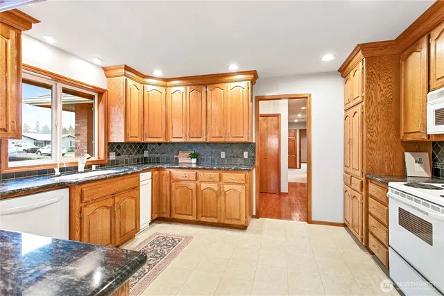 a large kitchen with stainless steel appliances granite countertop a stove a sink and a refrigerator
