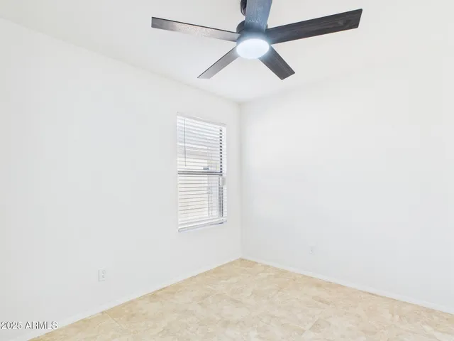 an empty room with a window and a fan
