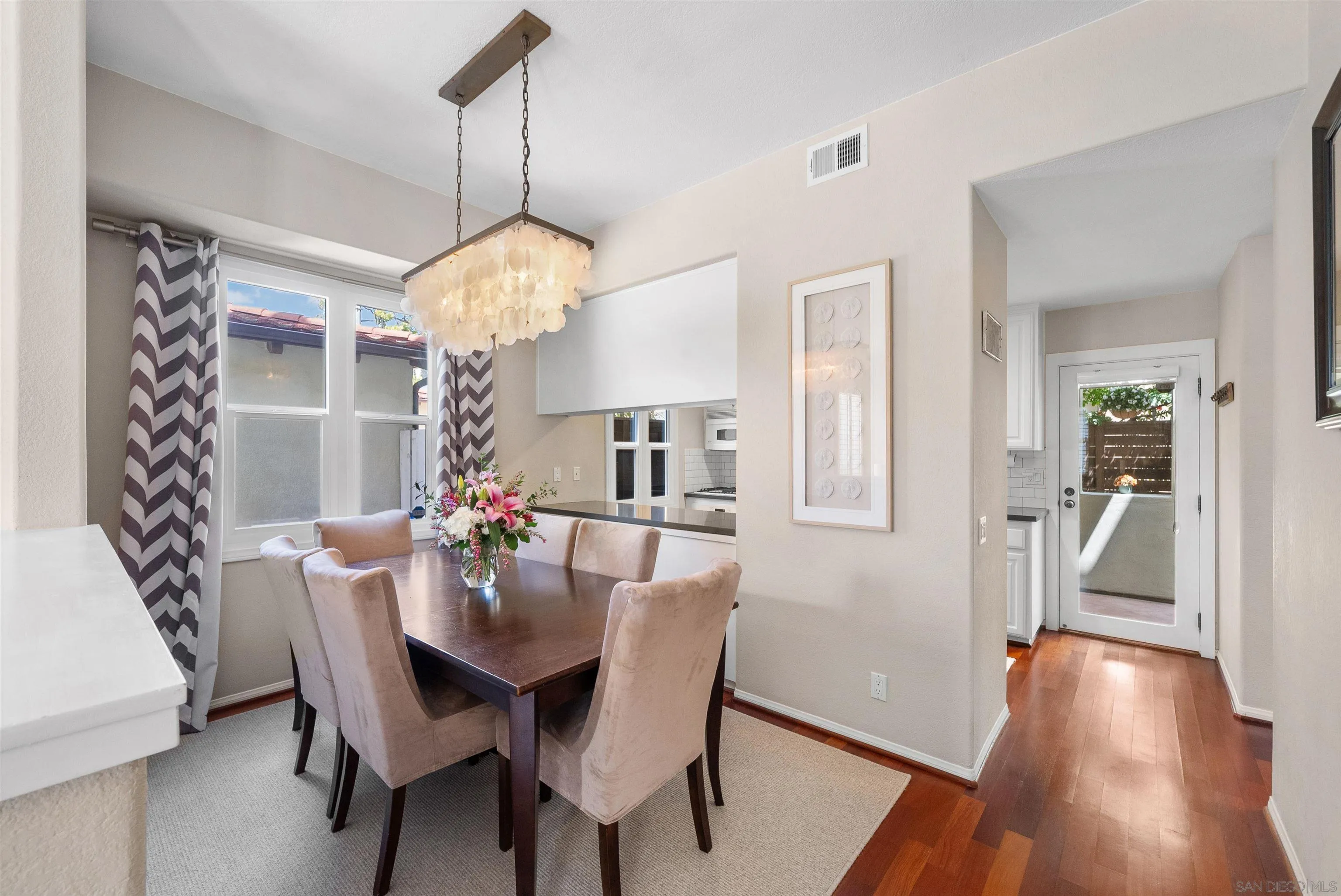 6755 Tyrian Street La Jolla, CA 92037 - Photo 11 of 60 a dining room with wooden floor a chandelier a wooden table and chairs