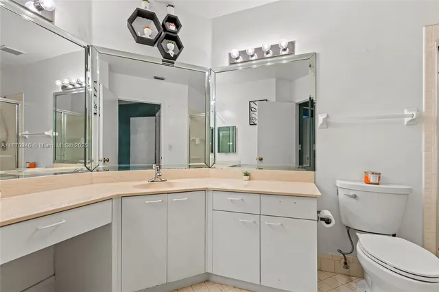 a bathroom with a sink a toilet a mirror a vanity and shower