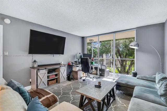 a living room with furniture a flat screen tv and a floor to ceiling window