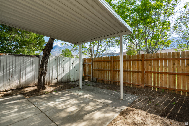 728 400 East Orem, UT 84097 - Photo 14 of 30 Covered patio area with a concrete slab, framed by a wooden privacy fence, and featuring a mature tree