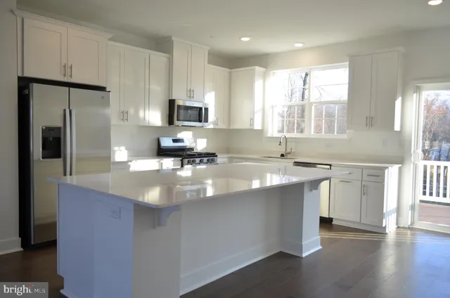 a kitchen with kitchen island granite countertop a sink appliances cabinets and a counter top space