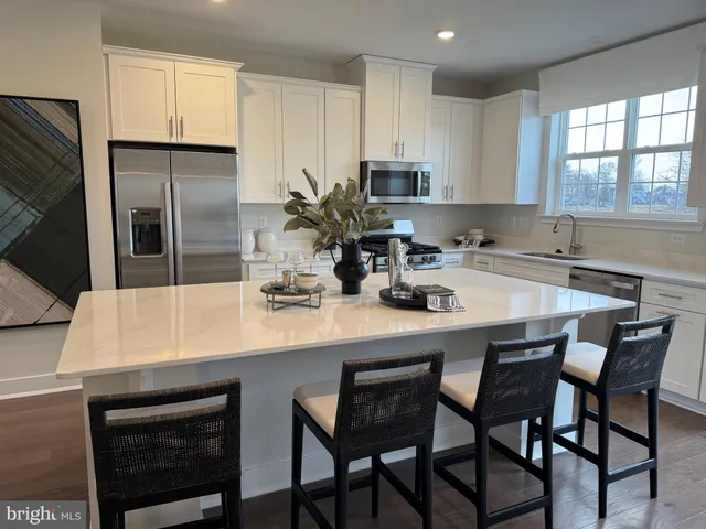 a kitchen with stainless steel appliances a table chairs refrigerator and microwave