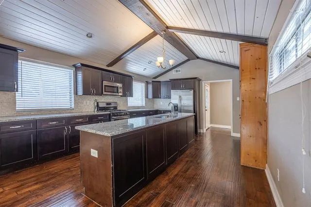 a kitchen with stainless steel appliances granite countertop a stove cabinets and wooden floor