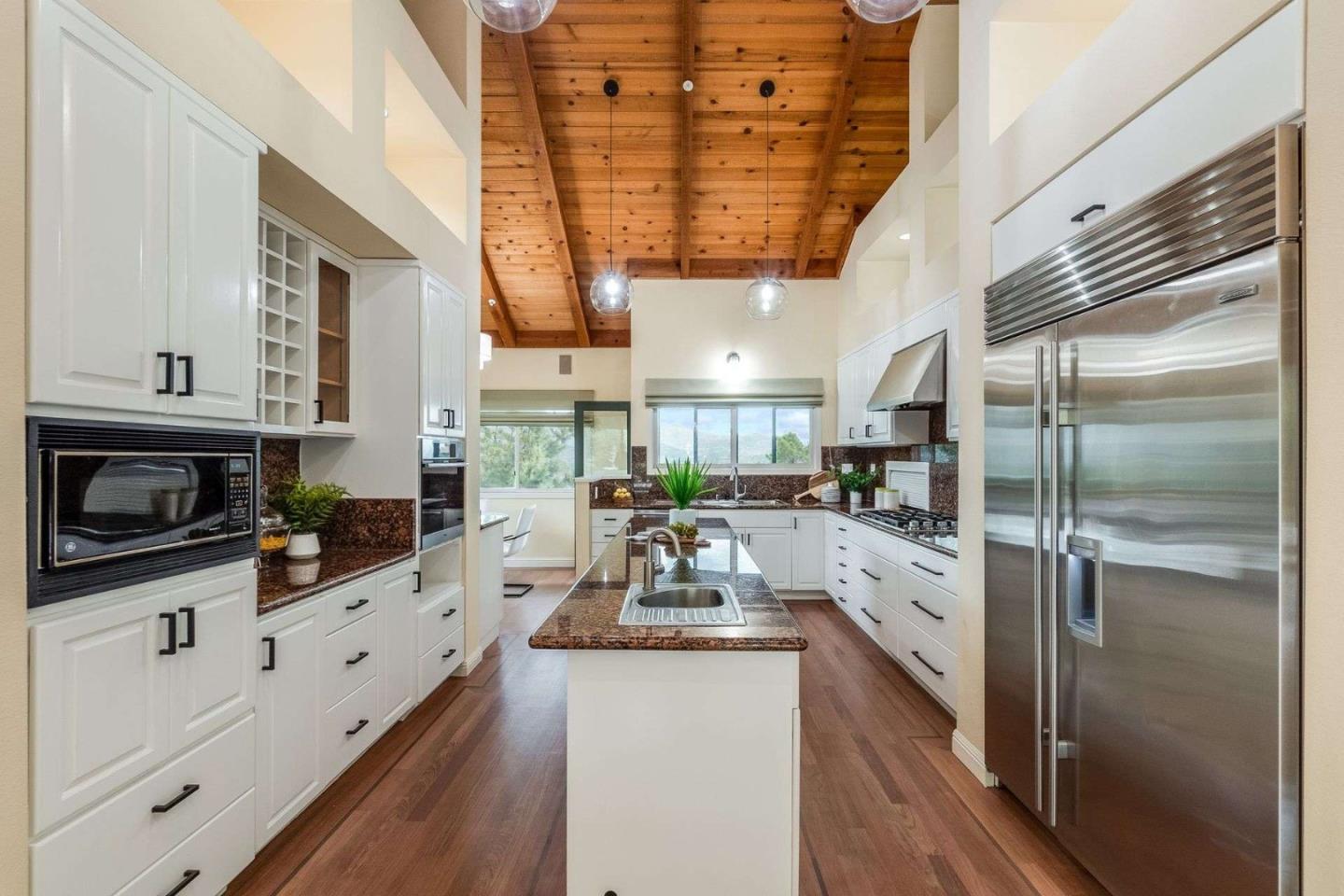 22340 Regnart Road Cupertino, CA 95014 - Photo 4 of 74 a kitchen with stainless steel appliances kitchen island granite countertop a refrigerator a oven a sink and white cabinets with wooden floor