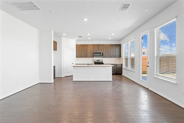 a view of kitchen with kitchen island a sink wooden floor and a refrigerator