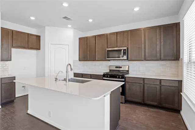 a kitchen with stainless steel appliances granite countertop a sink stove microwave and refrigerator