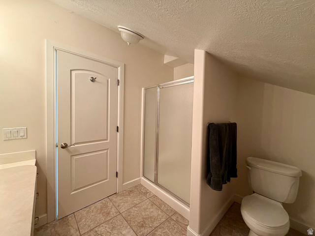 1133 Paris Canyon Road Paris, ID 83261 - Photo 28 of 75 Bathroom featuring a glass-enclosed shower, a toilet, a light-toned vanity countertop, a paneled door, and square tiled flooring