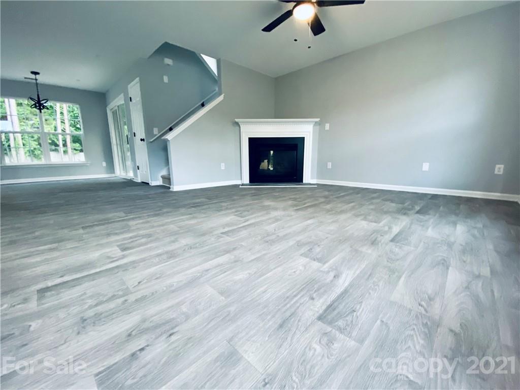 4916 Deerton Road Charlotte, NC 28269 - Photo 3 of 6 an empty room with a fireplace and wooden floor