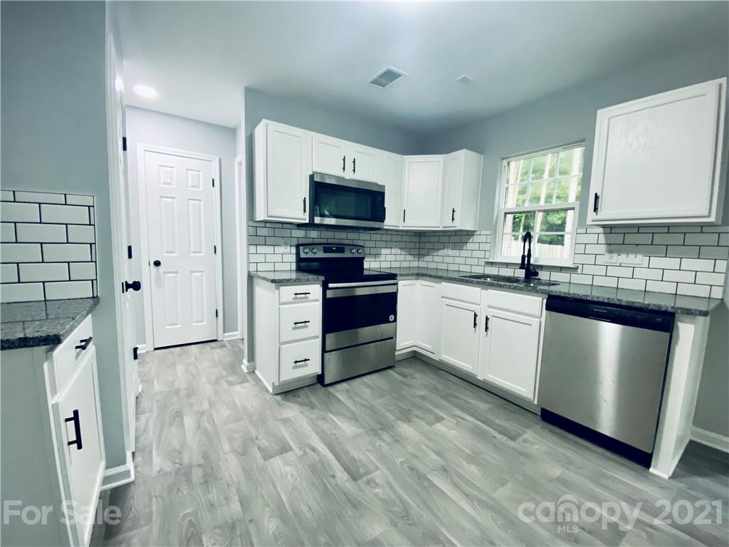 4916 Deerton Road Charlotte, NC 28269 - Photo 4 of 6 a kitchen with stainless steel appliances a sink a stove a refrigerator cabinets and a window