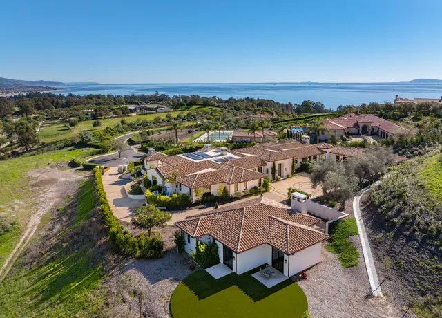 an aerial view of residential houses with outdoor space and ocean view