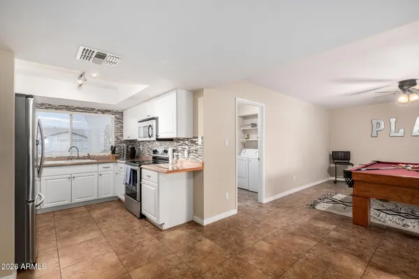 a kitchen with granite countertop stainless steel appliances a sink stove refrigerator and cabinets