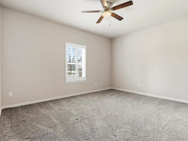 an empty room with a window and a fan