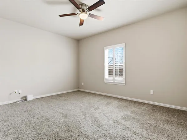 an empty room with a ceiling fan and window