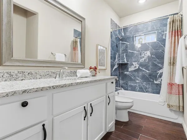 a bathroom with a granite countertop sink a mirror a toilet and a shower