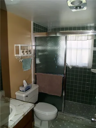 a bathroom with a granite countertop sink a toilet a mirror and shower