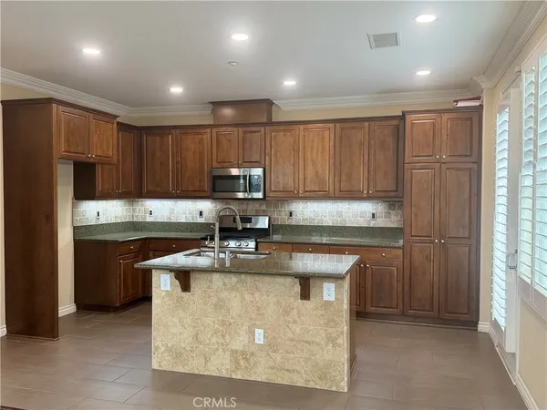 a kitchen with kitchen island granite countertop stainless steel appliances stove microwave refrigerator and sink