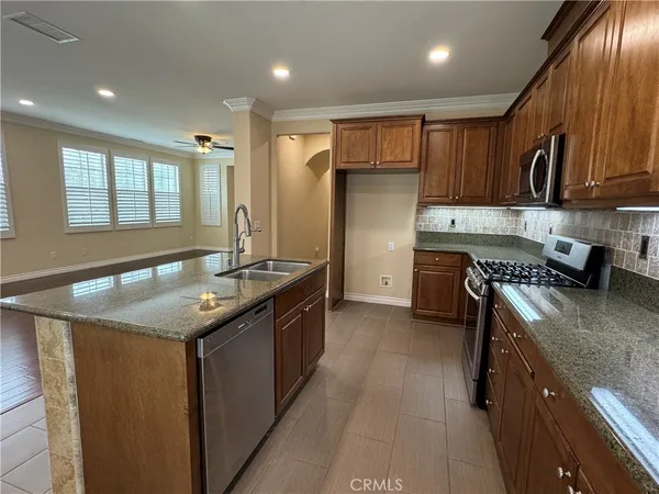 a kitchen with stainless steel appliances granite countertop a sink a stove and a refrigerator