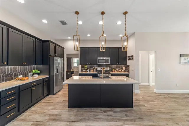 a kitchen with stainless steel appliances kitchen island granite countertop a refrigerator a sink and a stove