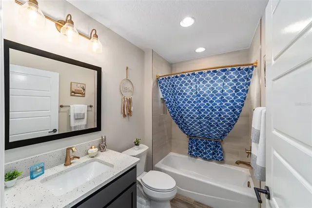 a bathroom with a granite countertop sink a toilet a mirror and shower