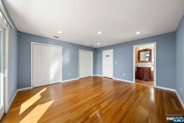 a view of an empty room with wooden floor and closet