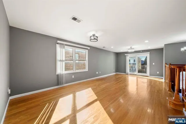 a view of an empty room with window and wooden floor