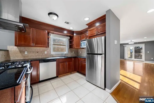 a kitchen with granite countertop stainless steel appliances a refrigerator stove top oven and sink