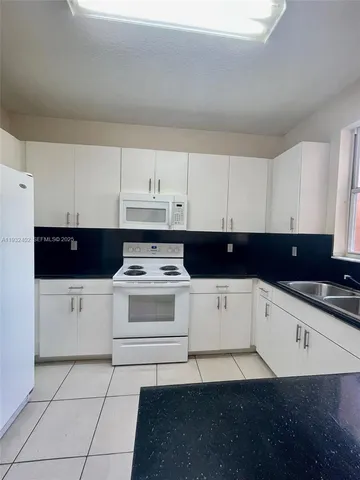 a view of kitchen with granite countertop white cabinets and black appliances