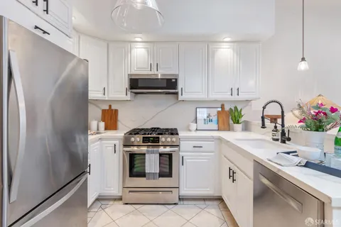 a kitchen with white cabinets stainless steel appliances and sink