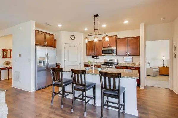 a kitchen with stainless steel appliances kitchen island granite countertop a table chairs and a refrigerator