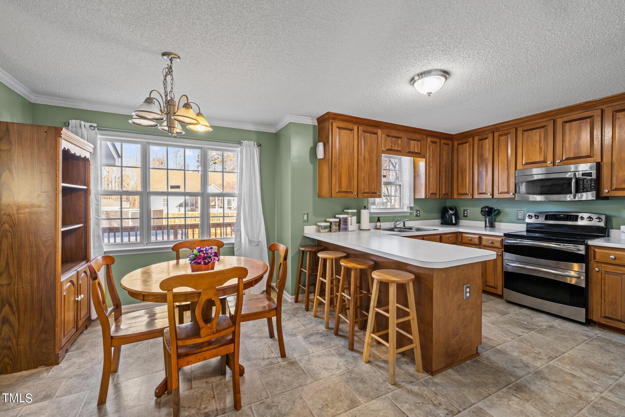 1516 Harvey Johnson Road Raleigh, NC 27603 - Photo 8 of 41 a kitchen with a stove a sink a dining table and chairs