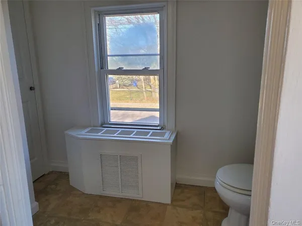 a bathroom with a granite countertop toilet a sink and a window