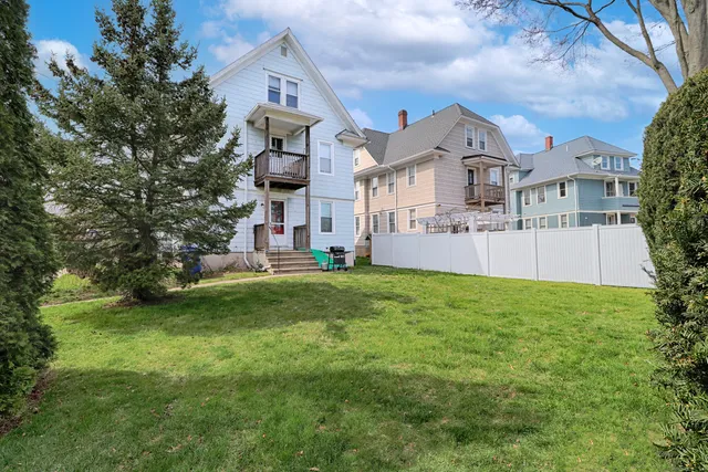 a view of a big house with a big yard and large trees
