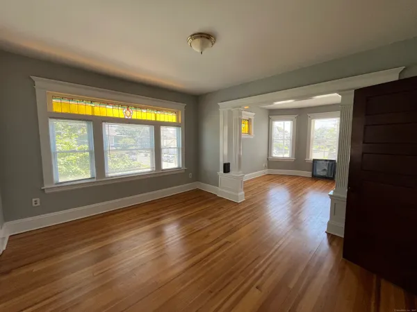 a view of an empty room with wooden floor and a window