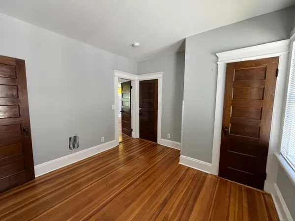 a view of an empty room with wooden floor and a window