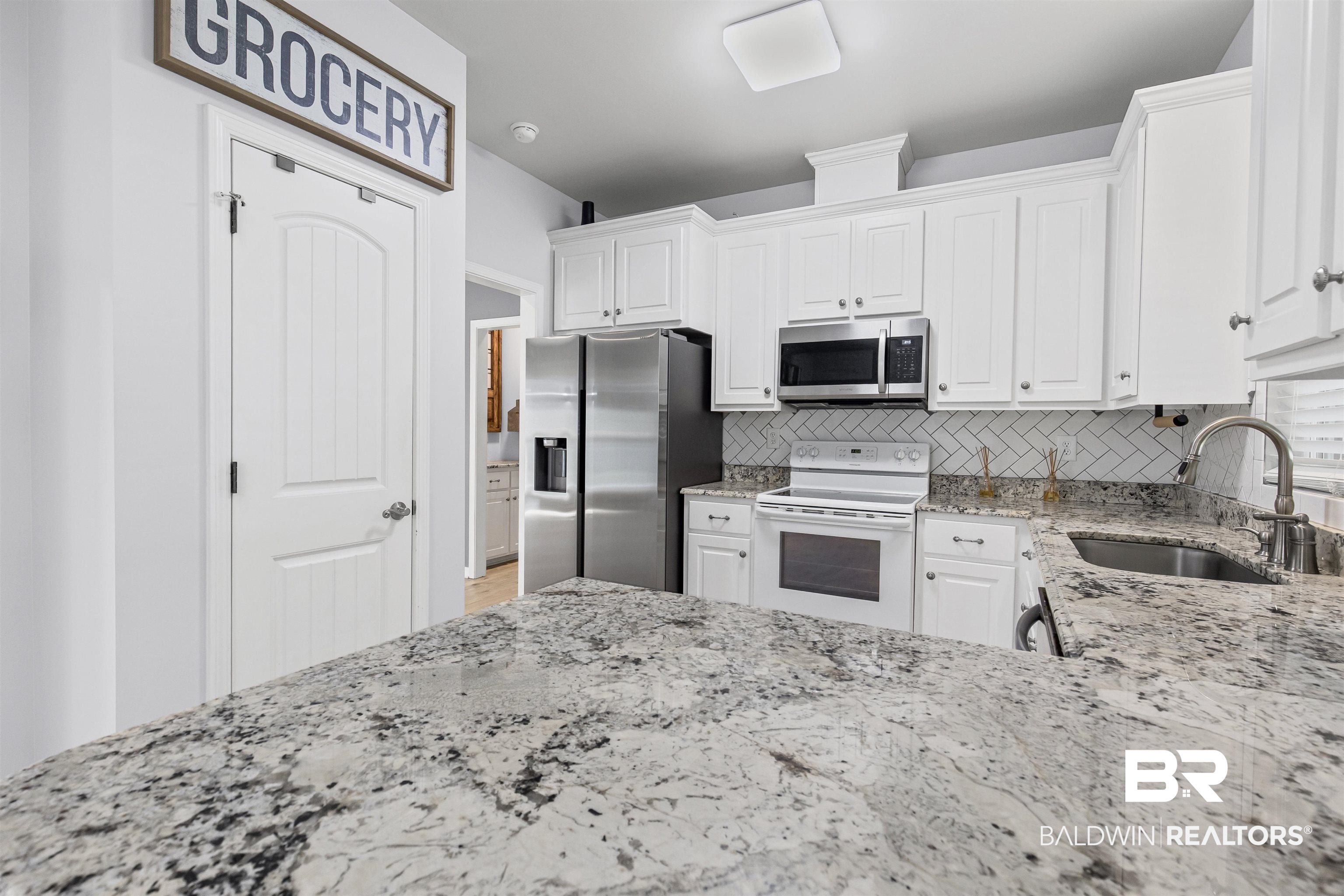 30851 Joseph Drive Spanish Fort, AL 36527 - Photo 6 of 22 Kitchen with light stone counters, stainless steel appliances, decorative backsplash, and white cabinets