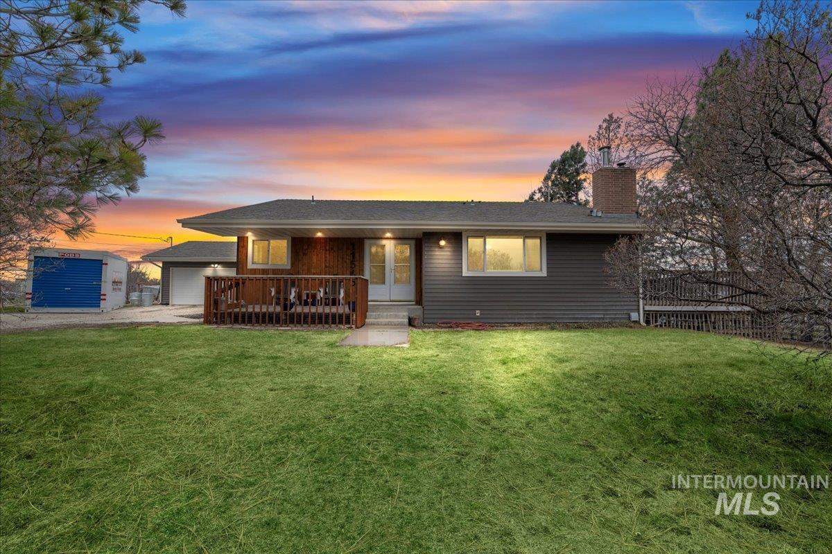 View of front facade with a chimney, a lawn, a garage, and driveway