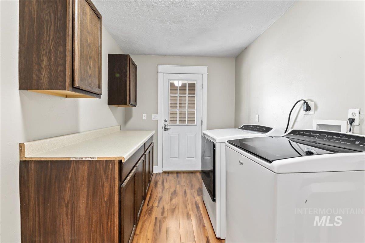 11545 Kuna Road Kuna, ID 83634 - Photo 18 of 50 Laundry room featuring a textured ceiling, light wood-style floors, and cabinet space