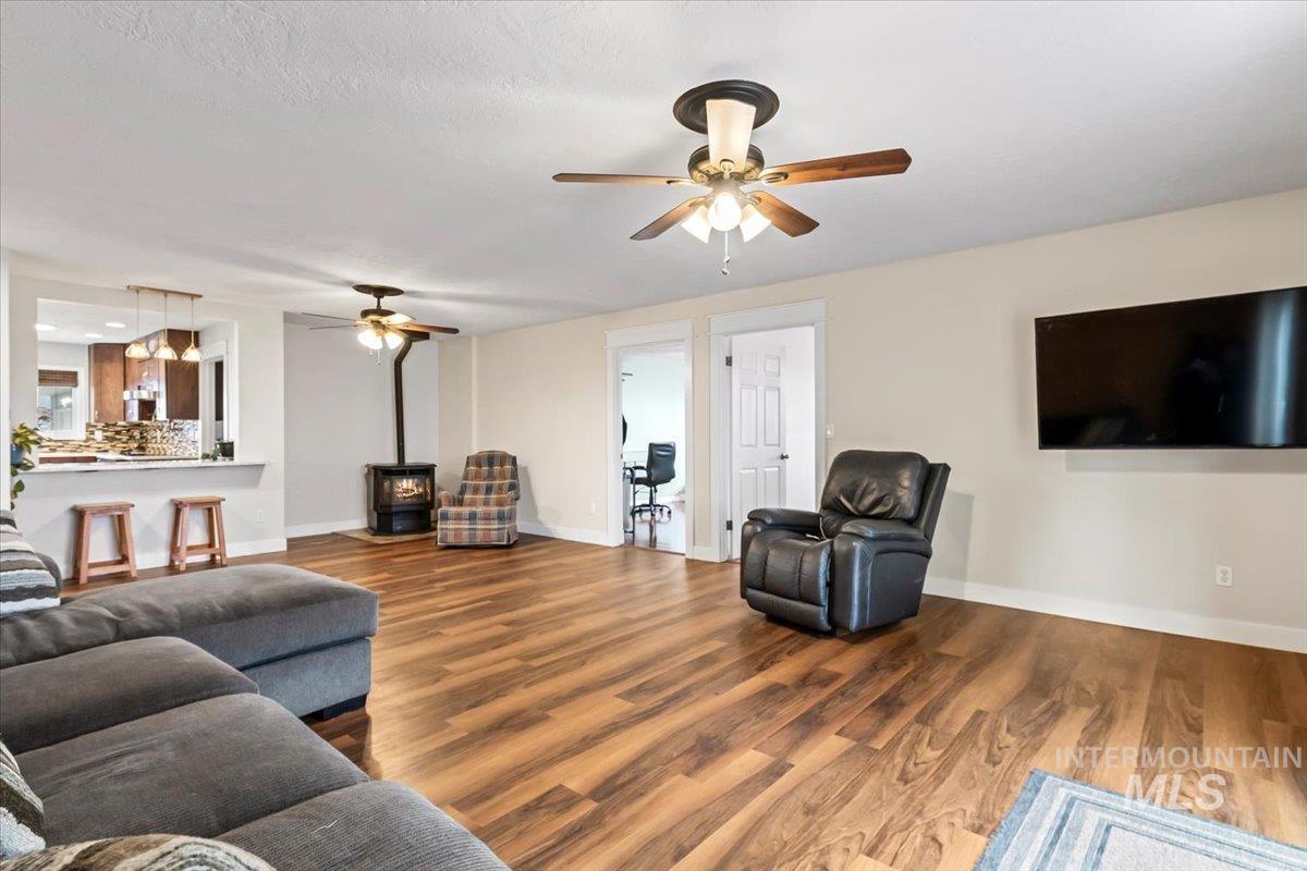 11545 Kuna Road Kuna, ID 83634 - Photo 22 of 50 Living area featuring a wood stove, wood finished floor, ceiling fan and wood stove