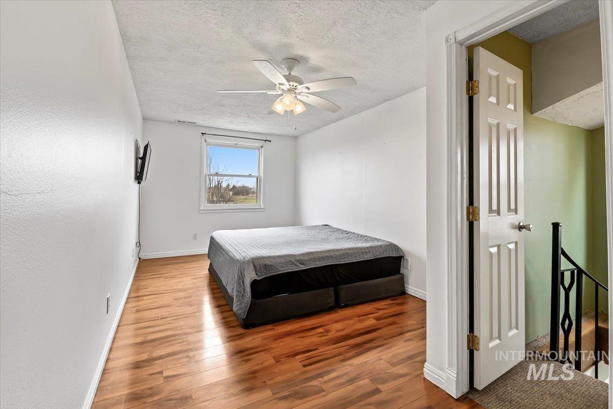 11545 Kuna Road Kuna, ID 83634 - Photo 27 of 50 3 upstairs Bedroom featuring wood finished floors, a textured ceiling, and ceiling fan with access to downstairs living area