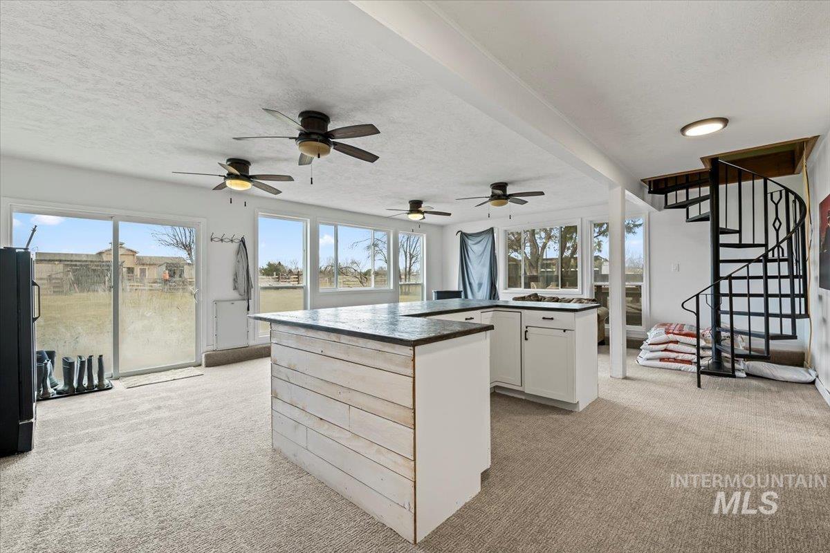 11545 Kuna Road Kuna, ID 83634 - Photo 28 of 50 Kitchen featuring light colored carpet, a center island, white cabinets, a textured ceiling, and plenty of natural light