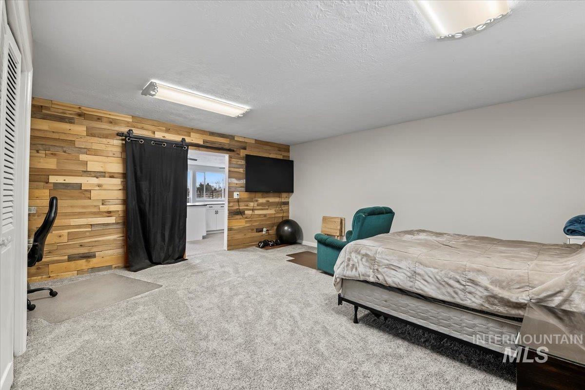 11545 Kuna Road Kuna, ID 83634 - Photo 30 of 50 downstairs Carpeted bedroom with wood walls and a barn door