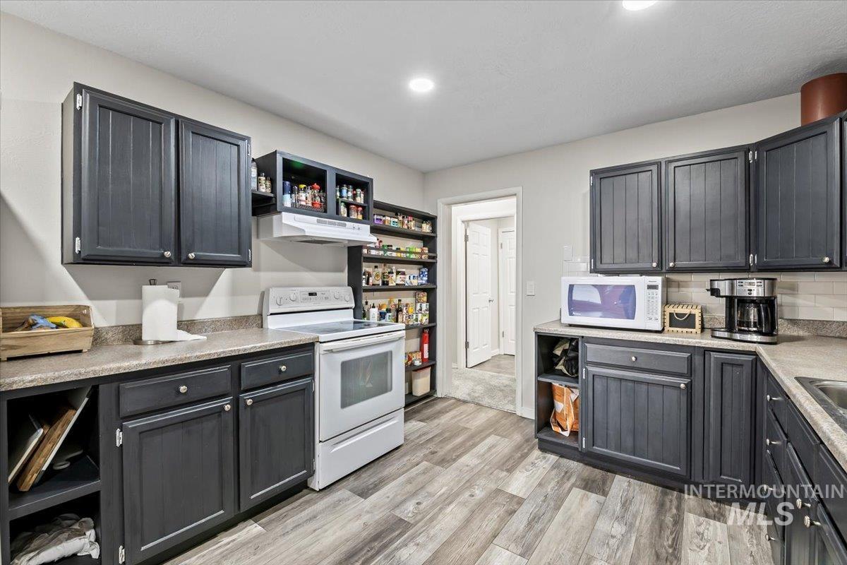 11545 Kuna Road Kuna, ID 83634 - Photo 33 of 50 Kitchen with open shelves, white appliances, light countertops, light wood-style flooring, and decorative backsplash