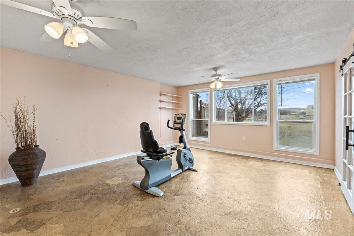 11545 Kuna Road Kuna, ID 83634 - Photo 34 of 50 Exercise area featuring a ceiling fan, a textured ceiling, and a barn door